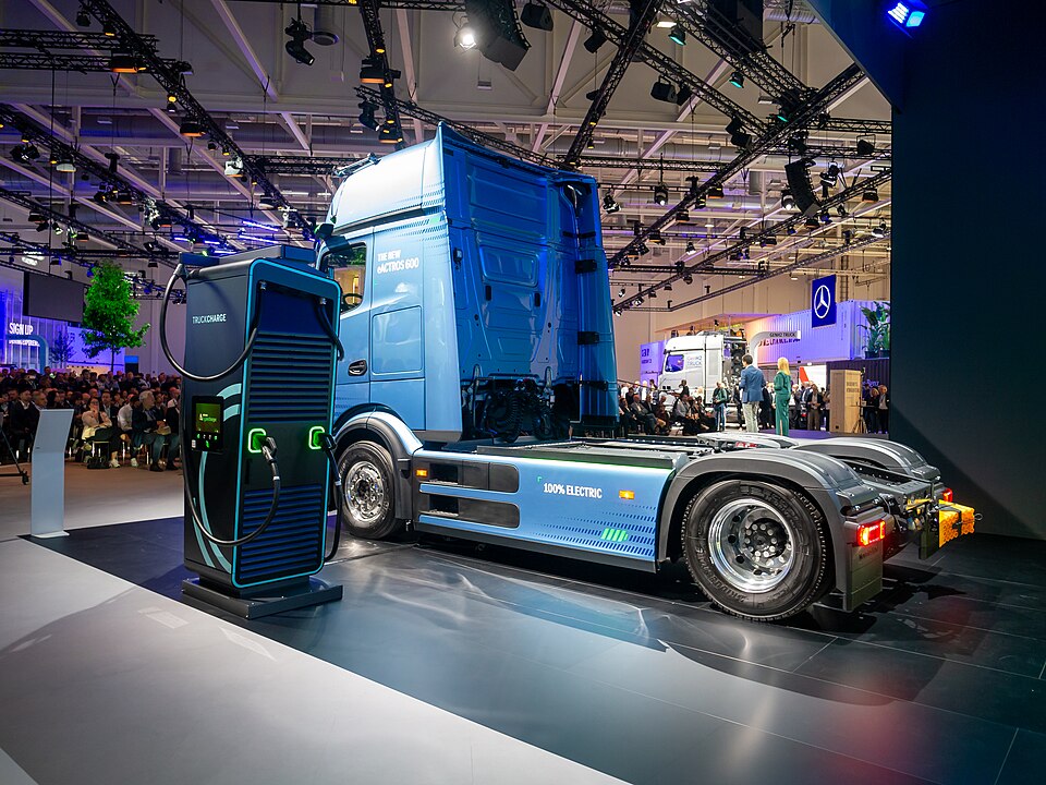 Blauer Mercedes-Benz eActros 600 schräg von hinten neben einer Ladeanlage auf der IAA 2024