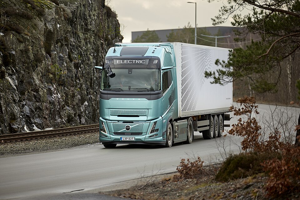 Türkisfarbener Volvo FH Aero Electric mit weißem Auflieger auf einer Landstraße
